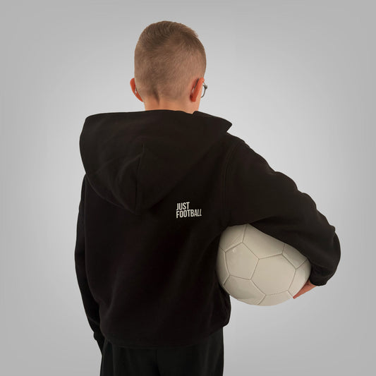 Back of black ONETWENTI Just Football hoodie worn by younger boy model with football