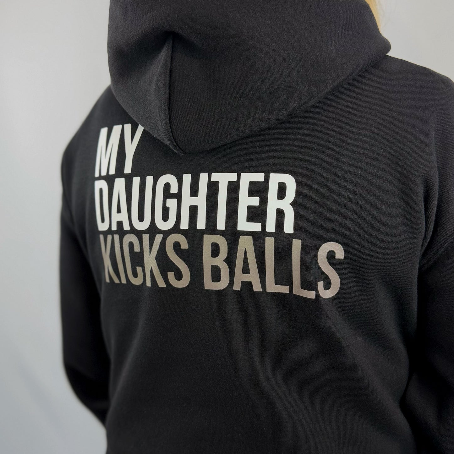Close up view of a female model wearing the ONETWENTI My Daughter Kicks Balls relaxed fit hoodie in black.