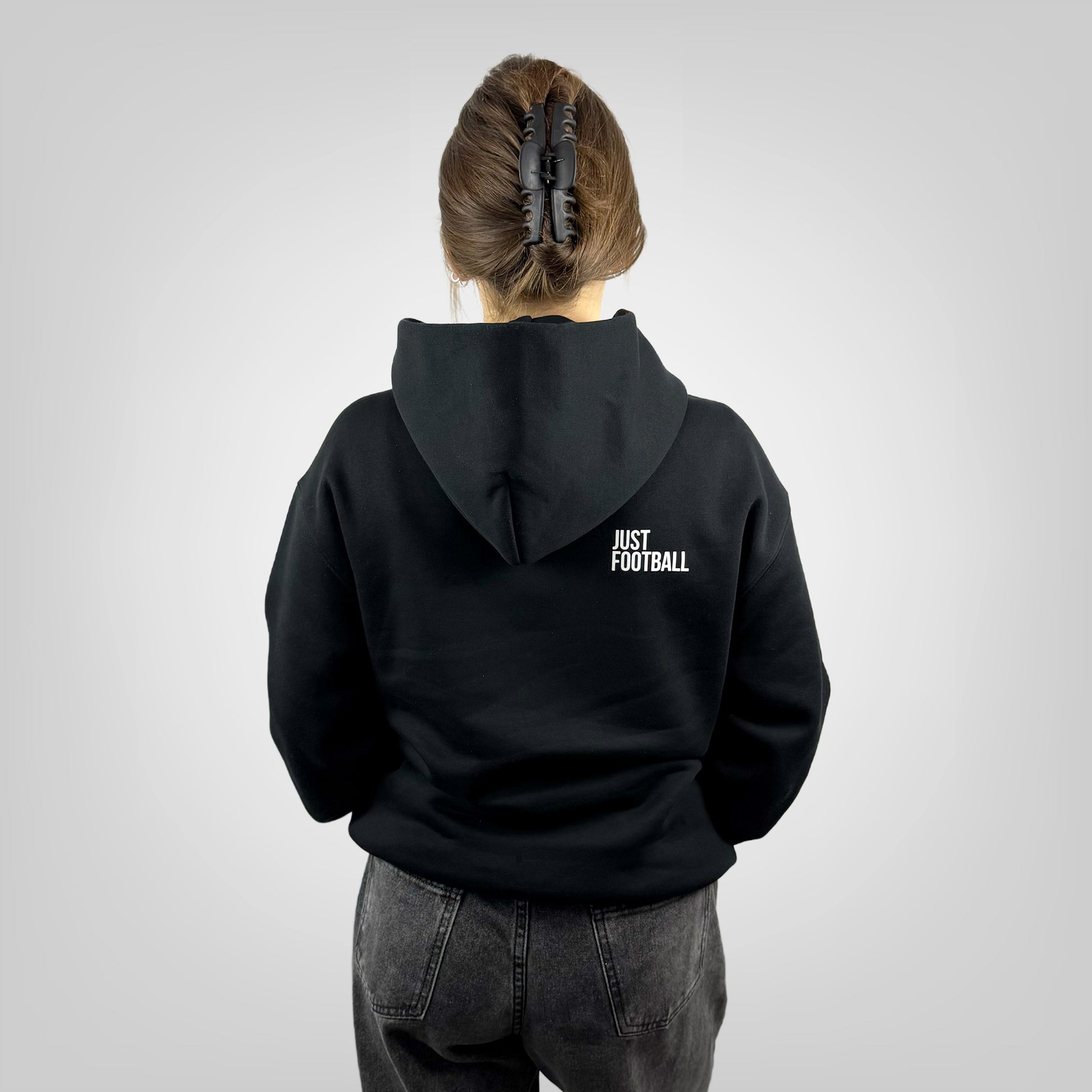 Person wearing a ONETWENTI black hoodie with 'Just Football' text on the back, standing against a plain background