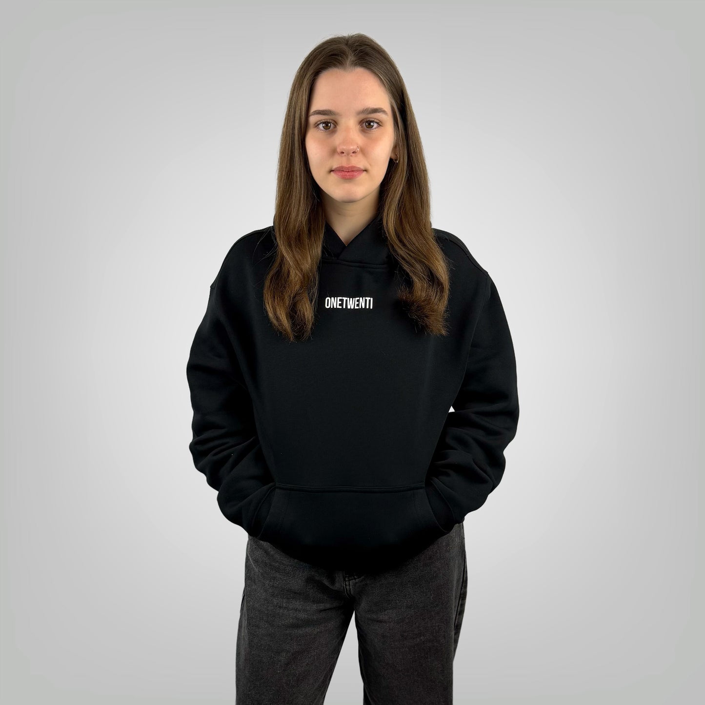 Female model wearing the ONETWENTI Its Just Football relaxed fit hoodie in black against a white background