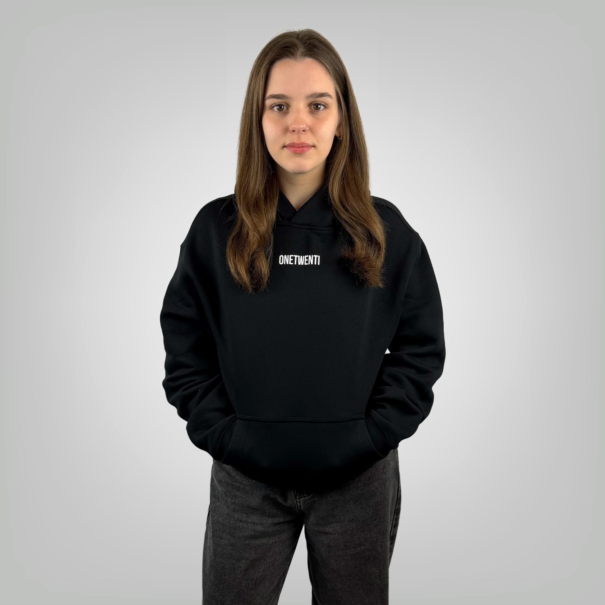 Female model wearing the ONETWENTI Its Just Football relaxed fit hoodie in black against a white background