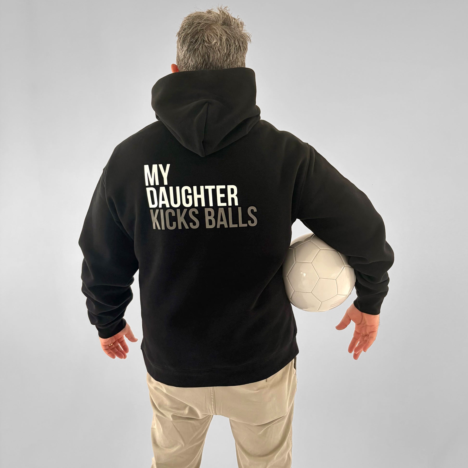 Back of black ONETWENTI My Daughter Kicks Balls hoodie worn by male model