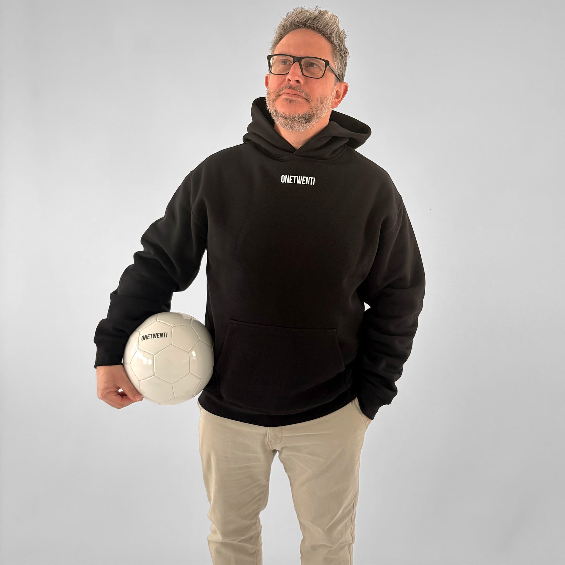 Front view of black ONETWENTI My Daughter Kicks Balls hoodie on male model standing