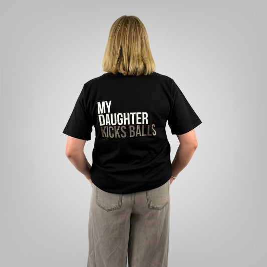 Woman wearing MY DAUGHTER KICKS BALLS black t-shirt with large back print, rear view on light grey background