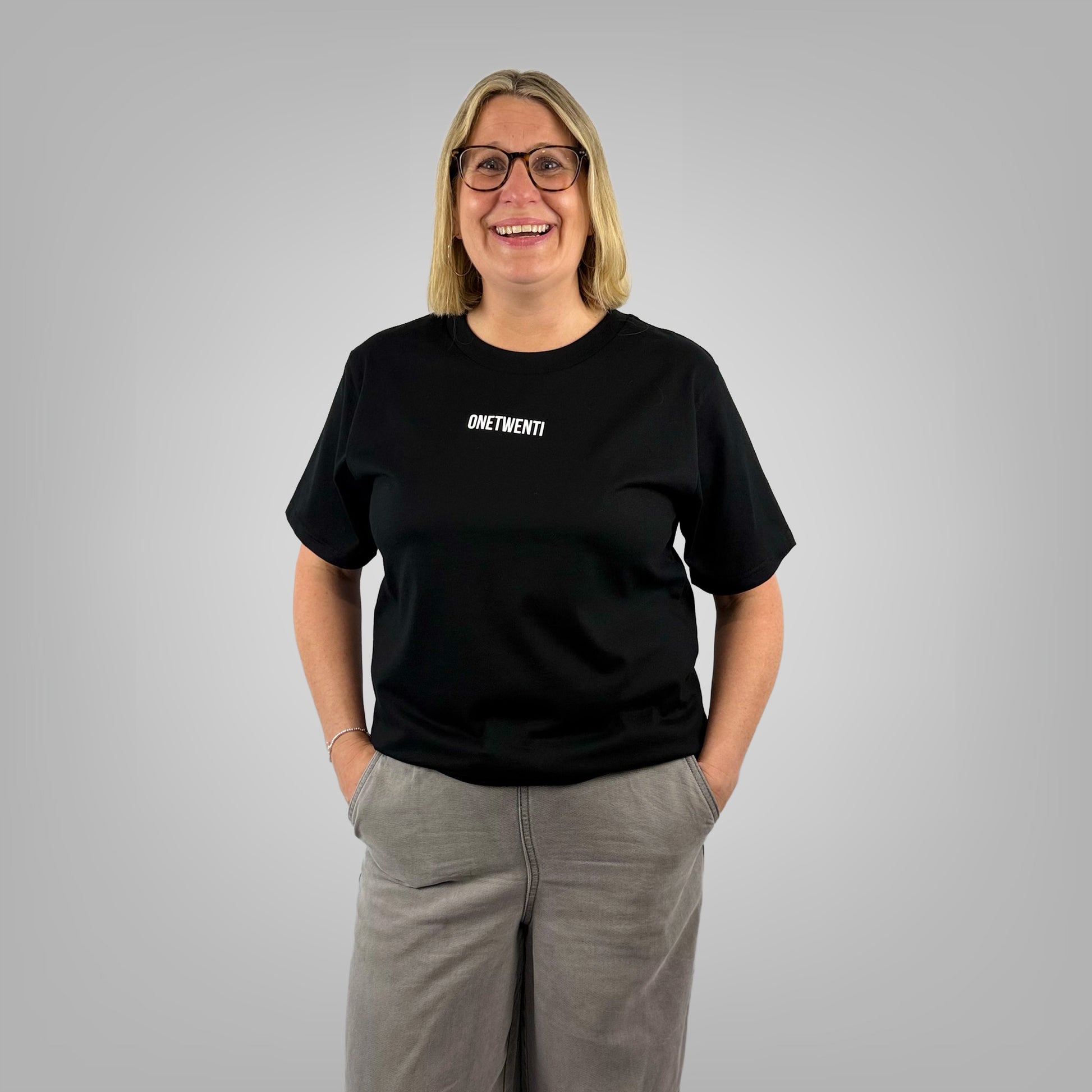 Woman wearing MY DAUGHTER KICKS BALLS black t-shirt, front view on light grey background