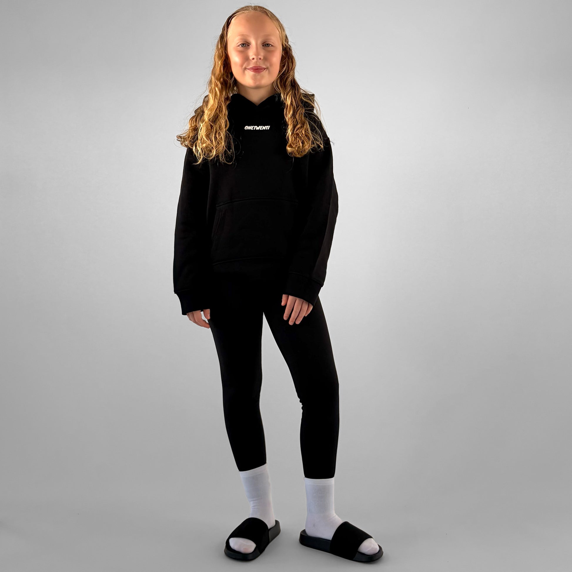 Front of black ONETWENTI This Girl’s Game Is Football hoodie worn by younger model
