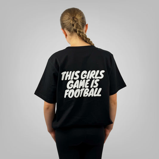 Woman wearing THIS GIRLS GAME IS FOOTBALL black t-shirt with large back print, rear view on light grey background