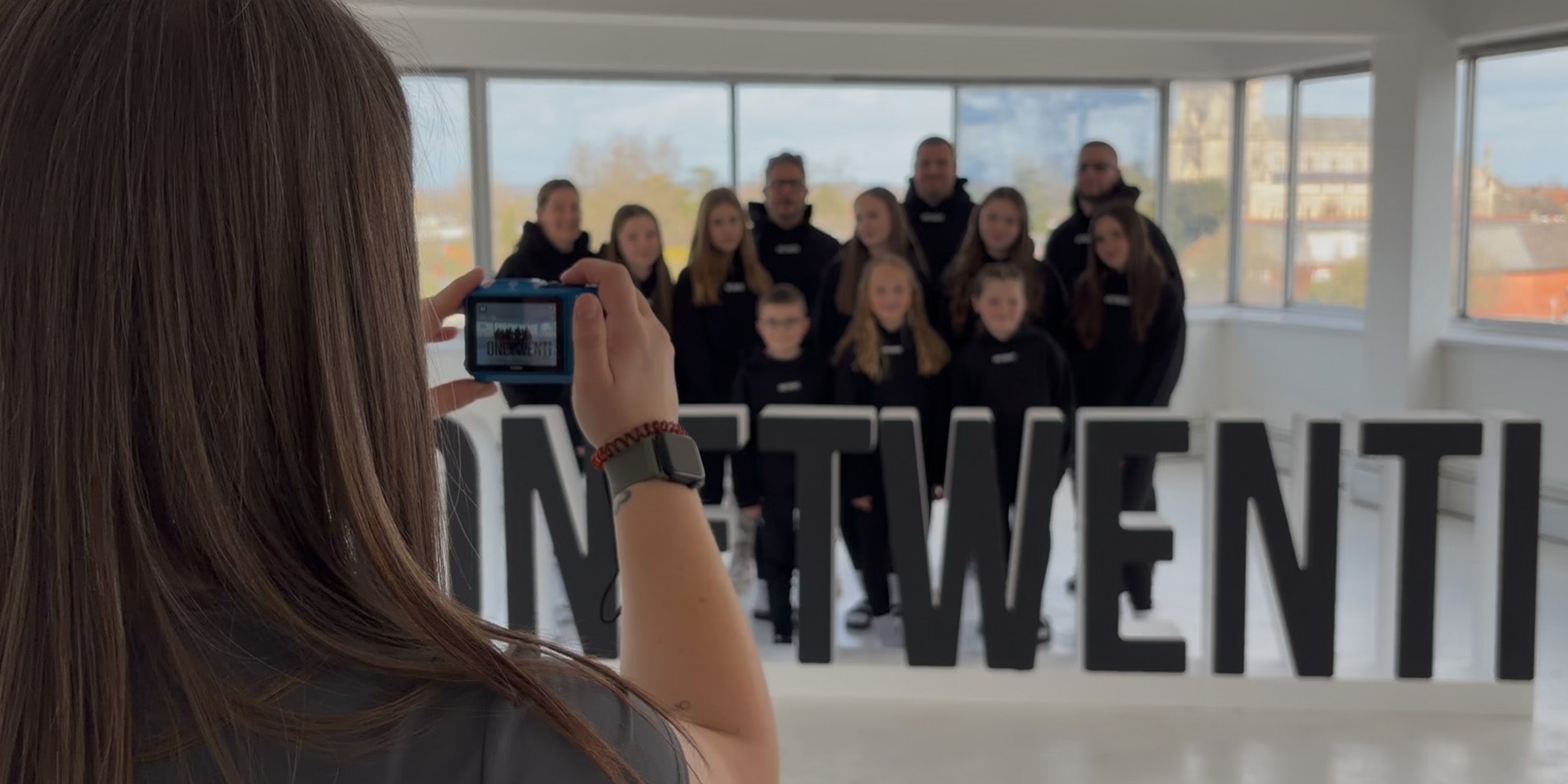 Group of ONETWENTI members posing for a photo in front of brand sign, representing the community behind the women’s game