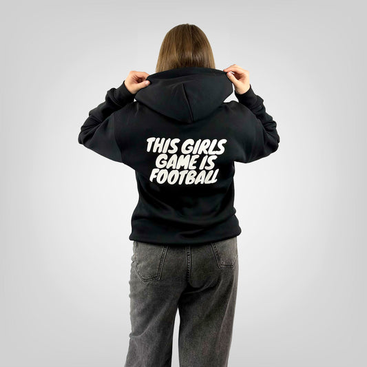 Back view of a female model wearing the ONETWENTI This Girls Game Is Football relaxed fit hoodie in black.